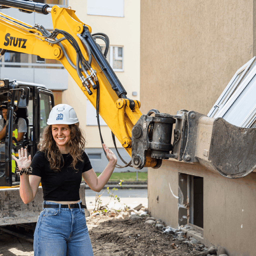 Studentin von zhaw auf Baustelle neben Bagger bei Bauarbeiten